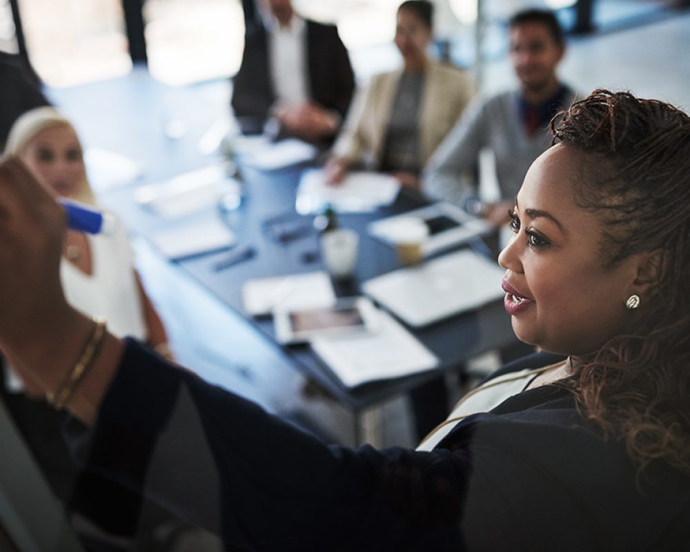 High angle shot of a young businesswoman explaining work related stuff during a presentation to work colleagues in a boardroom